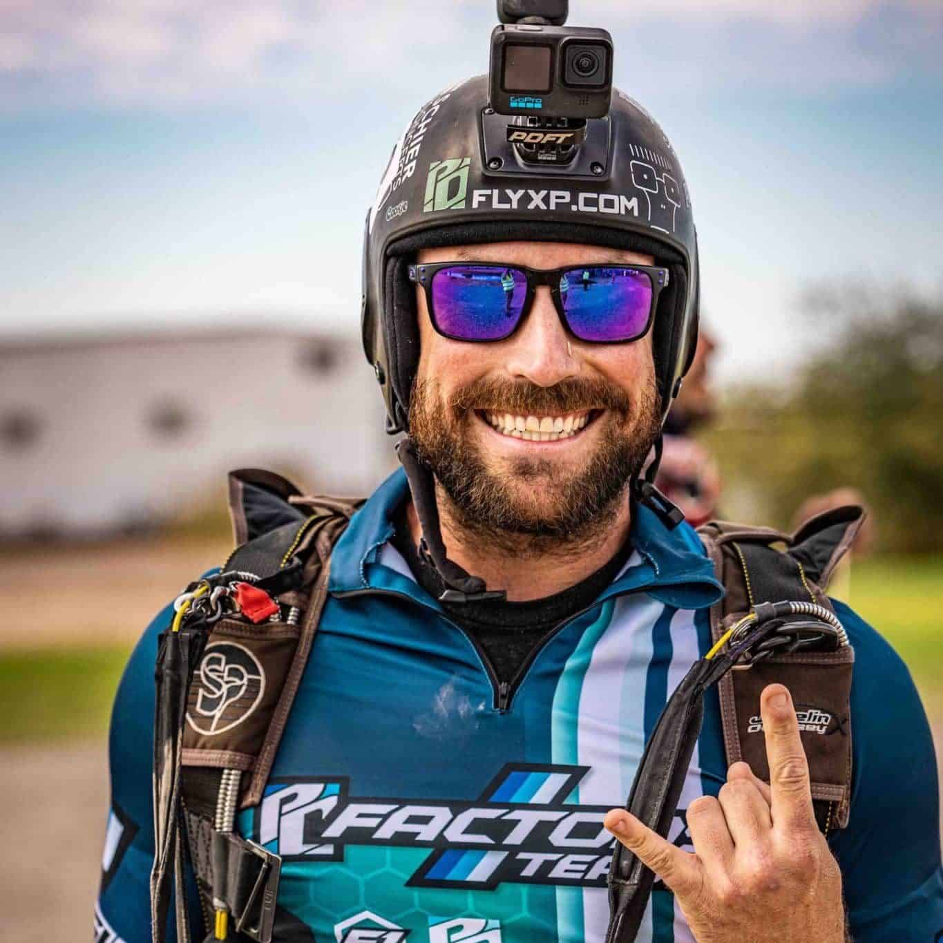 Skydiver wearing a Cookie open faced helmet and sunglasses give the rock on symbol